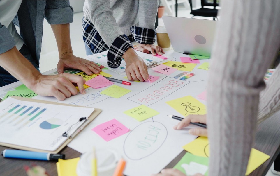 Manos organizando post-its en lluvia de ideas para estrategia de comunicación